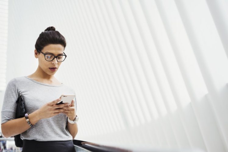 A woman checking social media on her phone, in a light airy space. A woman checking social media on her phone, in a light airy space.