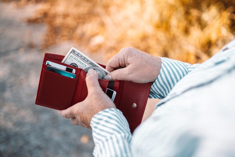 Unrecognizable female holding in hands wallet with 100 dollars money. Banking money, financial management, saving funds
