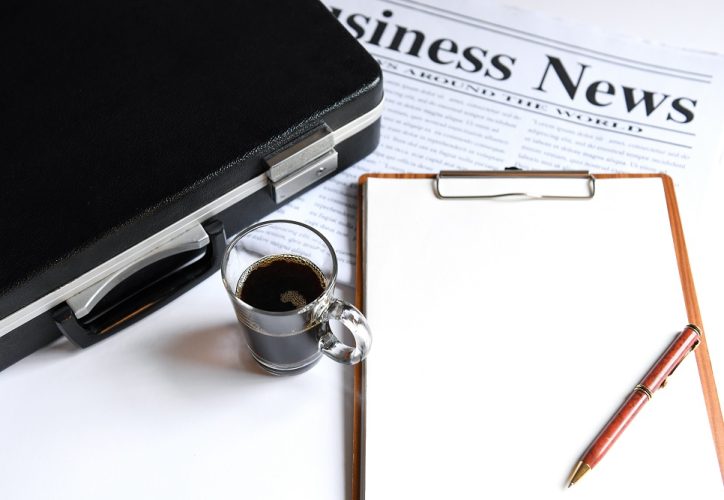 Coffee and briefcase with notebook on business newpaper.