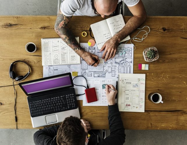 Colleagues Working on Web Design Startup Together on Wooden Table